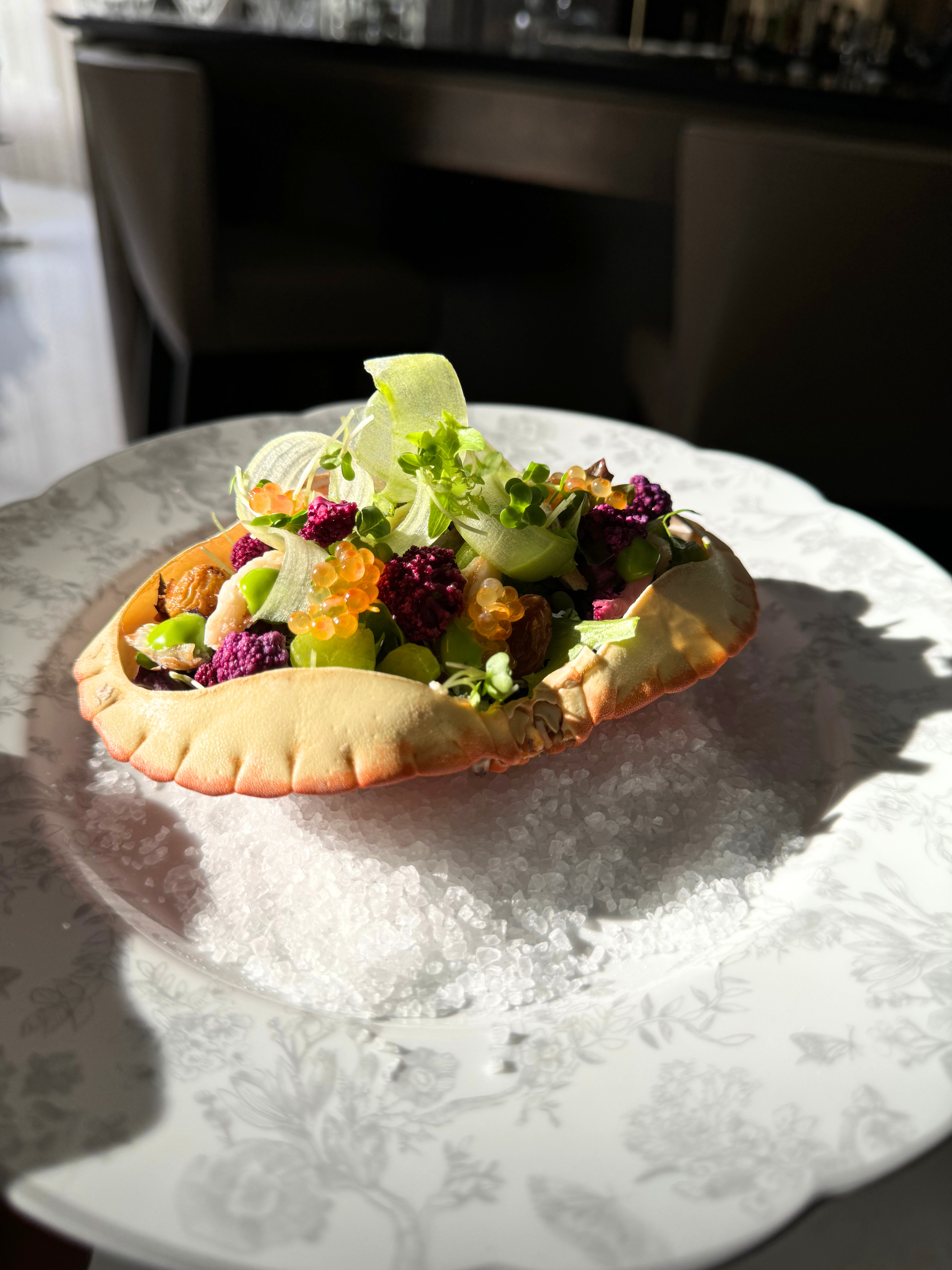 Dressed crab in the shell with salmon roe, micro herbs and shaved fennel, served on rock salt