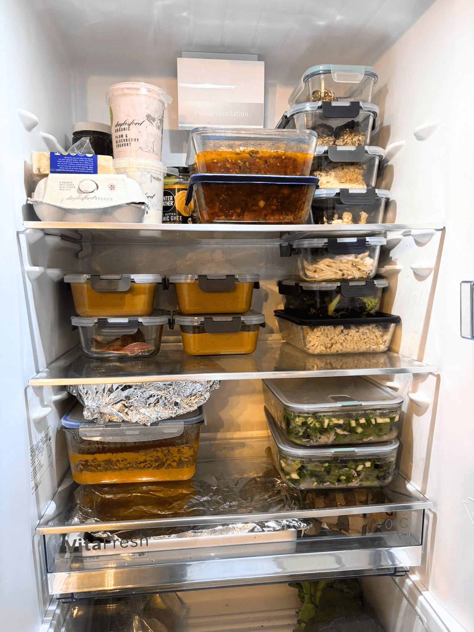 A client's fridge stocked with a week of chef-prepared meals in glass containers