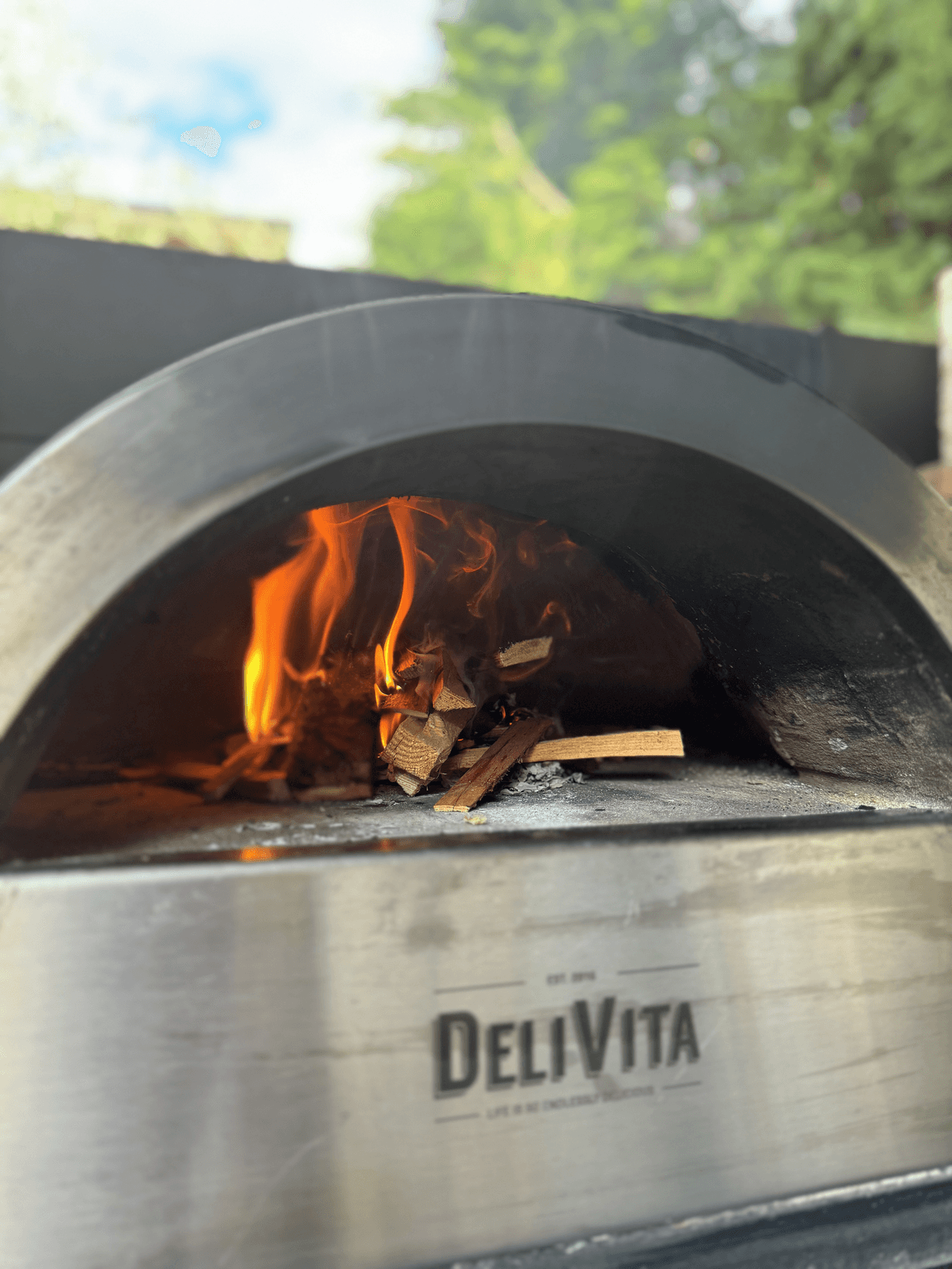 A wood-fired outdoor oven with logs burning inside