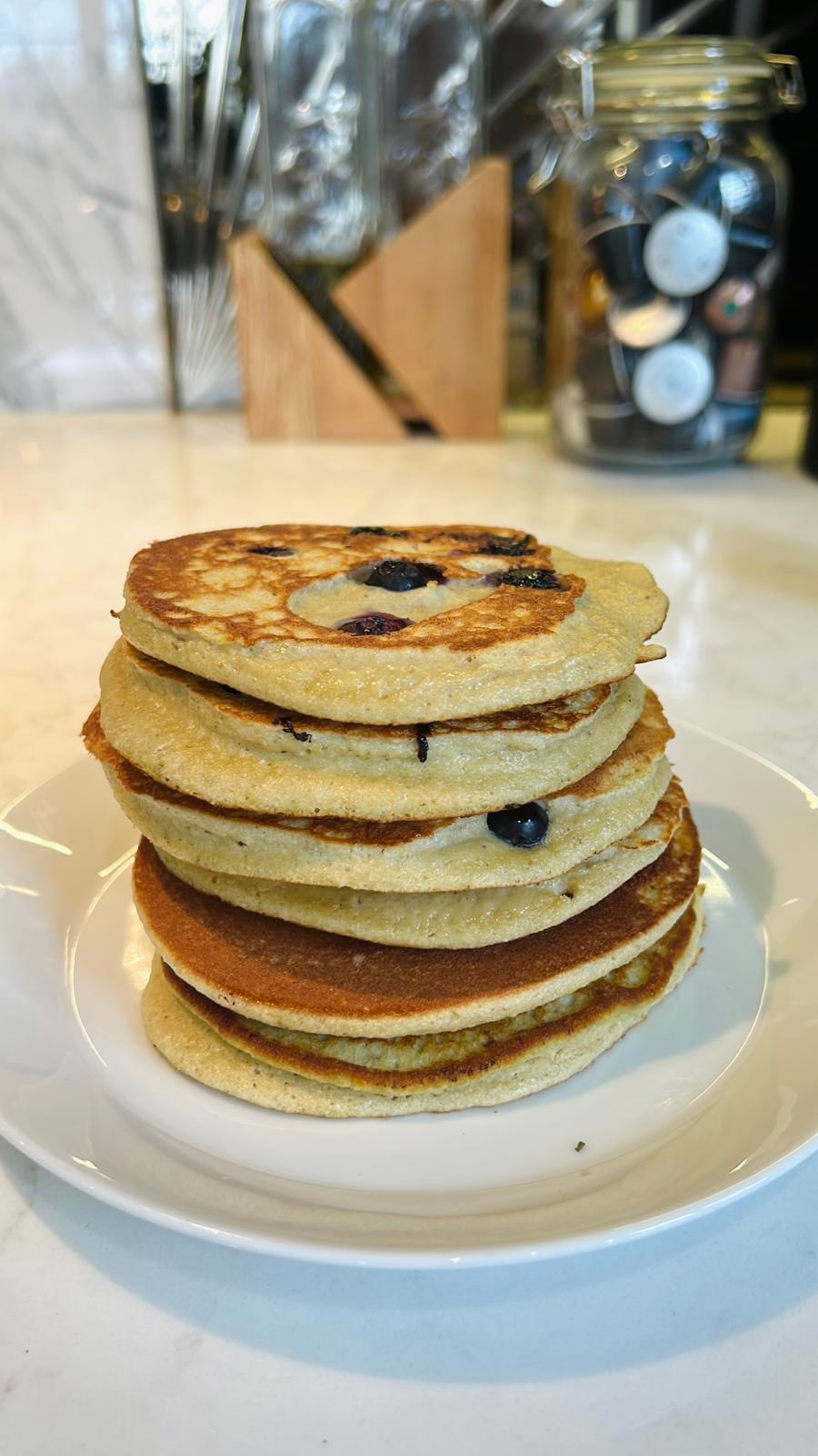 A stack of blueberry pancakes on a white plate