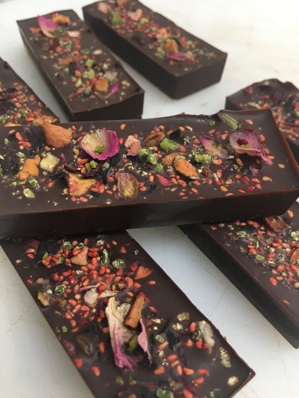 Bars of dark chocolate topped with dried fruit, seeds and edible flower petals