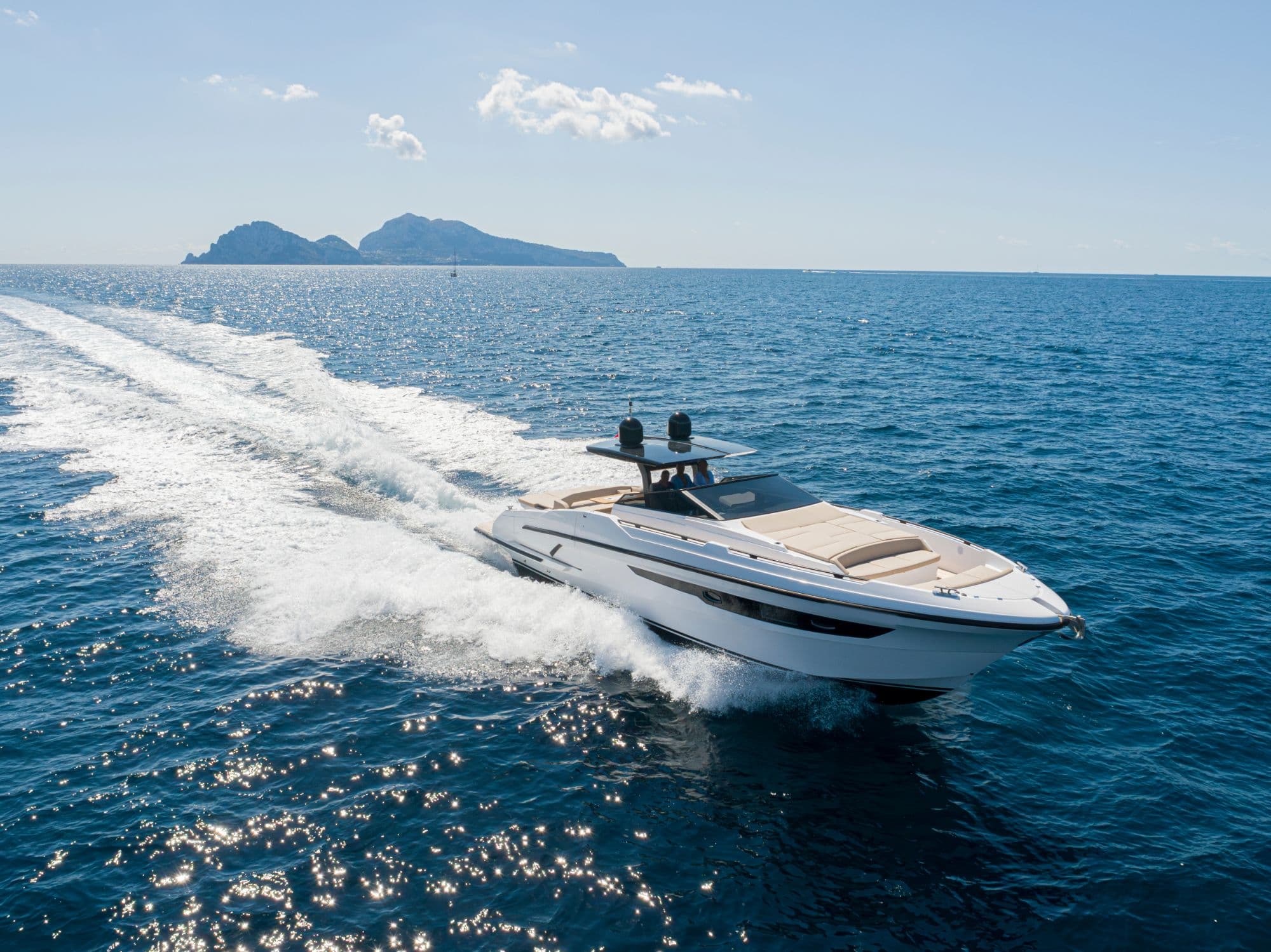 A motor yacht under way on open water, an island on the horizon